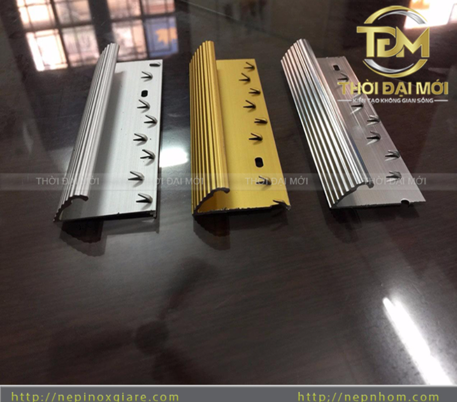 Khám phá toàn diện về nẹp nhôm và nẹp inox với hàng loạt ứng dụng thực tế trong thi công nội thất, ngoại thất: nẹp sàn, nẹp góc, nẹp LED, nẹp cầu thang, nẹp trang trí... Lợi ích, cách chọn, mẹo thi công và kinh nghiệm thực tế từ chuyên gia nepnhom.com. Giải pháp hoàn thiện chi tiết bền đẹp, sang trọng cho mọi công trình. Trong bối cảnh ngành nội thất và xây dựng Việt Nam đang phát triển mạnh mẽ với xu hướng tối giản, hiện đại và bền vững, nẹp nhôm cùng nẹp inox đã khẳng định vị thế là những “người hùng thầm lặng” của mọi công trình. Không chỉ đóng vai trò kỹ thuật che khe nối, bảo vệ cạnh vật liệu, chúng còn là yếu tố then chốt tạo nên sự tinh tế, sang trọng và chuyên nghiệp cho không gian sống và làm việc. Theo kinh nghiệm thi công thực tế tại hàng trăm dự án từ nhà phố, chung cư cao cấp đến showroom, văn phòng và khách sạn, việc sử dụng đúng loại nẹp nhôm inox có thể nâng tầm thẩm mỹ lên đáng kể trong khi giảm chi phí bảo trì lâu dài. Bài viết này sẽ phân tích chi tiết ứng dụng thực tế, lợi ích, cách lựa chọn và thi công tối ưu nhất cho sản phẩm này. Nẹp nhôm inox là gì? Đặc điểm kỹ thuật nổi bật Nẹp nhôm (Aluminum profile) được sản xuất từ hợp kim nhôm cao cấp (thường là 6063), qua quy trình định hình extrusion và xử lý bề mặt anode hoặc sơn tĩnh điện. Chúng có độ nhẹ, dễ gia công, khả năng chống oxy hóa tốt và giá thành hợp lý. Nẹp inox chủ yếu là inox 304 (chống gỉ cao cấp) hoặc inox 201, nổi bật với độ sáng bóng gương, khả năng chịu lực và chịu môi trường khắc nghiệt (ẩm ướt, hóa chất). Các đặc điểm chung nổi bật: • Độ bền cao: Tuổi thọ 10-20 năm hoặc hơn nếu thi công đúng cách. • Đa dạng chủng loại: Chữ T, V, L, U, La, góc tròn, mặt bằng, len chân tường, luồn dây điện, LED... • Màu sắc phong phú: Inox gương, vàng champagne, đen titanium, trắng, vân gỗ, vân đá... • Dễ thi công, bảo trì và vệ sinh. • Thân thiện môi trường: Có thể tái chế. So sánh nhanh: Nẹp nhôm phù hợp cho hầu hết vị trí nội thất với chi phí thấp hơn, trong khi nẹp inox 304 lý tưởng cho khu vực ngoài trời, ẩm ướt hoặc đòi hỏi độ sang trọng cao. Ứng dụng thực tế đa dạng của nẹp nhôm inox 1. Nẹp sàn và nẹp chuyển tiếp vật liệu Một trong những ứng dụng phổ biến nhất là nẹp sàn nhôm và nẹp nối sàn. Khi thi công sàn gỗ công nghiệp, sàn nhựa hèm khóa hay gạch porcelain kết hợp với thảm hoặc đá, nẹp chữ T hoặc nẹp kết thúc giúp: • Che khe giãn nở nhiệt (tránh cong vênh, nứt). • Tạo đường phân cách thẩm mỹ. • Bảo vệ mép sàn khỏi mẻ, bong. Ví dụ thực tế: Trong các căn hộ chung cư cao cấp tại TP.HCM, nẹp nhôm nối sàn gỗ – gạch giúp chuyển tiếp mượt mà giữa phòng khách và khu vực bếp, tránh bụi bẩn tích tụ và dễ lau chùi. 2. Nẹp góc tường, nẹp bo góc và nẹp inox góc vuông Góc tường luôn là vị trí dễ va chạm nhất, đặc biệt trong nhà có trẻ em hoặc khu vực công cộng. Nẹp inox góc (chữ V, L, góc tròn) mang lại: • Bảo vệ cạnh gạch, đá khỏi sứt mẻ. • Tạo đường nét thẳng gọn, hiện đại. • Giảm chi phí sửa chữa lâu dài. Ứng dụng thực tế: Cầu thang, hành lang chung cư, vách TV, cột nhà, góc bếp. Nẹp inox góc tròn IR10mm hoặc IR12mm được ưa chuộng vì an toàn và thẩm mỹ cao. 3. Nẹp trang trí tường, vách và phào chỉ Nẹp nhôm chữ U, La inox, nẹp T: tạo chỉ tường 3D, khung tranh, đường line âm trên vách thạch cao hoặc vách gỗ. Kết hợp sơn bả hoặc giấy dán tường tạo hiệu ứng luxury mà chi phí chỉ bằng một phần so với vật liệu đắt tiền. Nhiều showroom nội thất sử dụng la inox trang trí chạy dọc vách tạo cảm giác không gian rộng hơn và cao cấp hơn. 4. Nẹp LED nhôm và hệ thống chiếu sáng gián tiếp Nẹp LED nhôm là xu hướng không thể thiếu trong thiết kế hiện đại. Có thể lắp âm trần, âm tường, âm sàn, dán nổi hoặc kết hợp với trần thạch cao. Lợi ích: • Tản nhiệt tốt, kéo dài tuổi thọ LED. • Tạo không khí ấm cúng cho phòng khách, phòng ngủ, quán cafe, spa. • Kết hợp nẹp inox sáng bóng cho hiệu ứng cao cấp. 5. Nẹp cầu thang, nẹp chống trượt và nẹp mũi bậc Nẹp nhôm/inox cầu thang không chỉ chống trơn trượt mà còn bảo vệ mũi bậc đá hoặc gỗ. Có nhiều phương án thi công: xẻ rãnh, ốp nổi, dán mặt bằng. Ứng dụng thực tế: Nhà hàng, khách sạn, biệt thự, trường học – nơi lưu lượng người qua lại cao. 6. Nẹp thảm, len chân tường và nẹp luồn dây điện • Nẹp thảm nhôm: Phổ biến ở khách sạn 5 sao, văn phòng. • Len nhôm chân tường: Thay thế len gỗ truyền thống, hiện đại và bền màu. • Nẹp nhôm luồn dây điện: Giải pháp đi dây nổi cho nhà đã hoàn thiện mà không đục tường. 7. Ứng dụng ngoại thất và mặt dựng Nẹp nhôm composite, nẹp inox mặt dựng, viền ban công chịu nắng mưa, gió bão tốt, phù hợp cho mặt tiền nhà phố, biệt thự, tòa nhà thương mại. Lợi ích vượt trội khi sử dụng nẹp nhôm inox • Bền vững và tiết kiệm: Giảm đáng kể chi phí sửa chữa so với không dùng nẹp. • Thẩm mỹ cao: Tạo đường nét tinh tế, nâng tầm không gian. • An toàn: Chống trơn trượt, bảo vệ cạnh sắc nhọn. • Dễ thi công: Phù hợp cả công trình mới và cải tạo. • Đa dạng phối hợp: Kết hợp tốt với gỗ, đá, kính, thạch cao, sơn... Hướng dẫn chọn mua nẹp nhôm inox chất lượng 1. Xác định vị trí sử dụng (nội thất/ngoại thất, ẩm ướt hay khô ráo). 2. Ưu tiên inox 304 cho khu vực ngoài trời hoặc bếp/nhà tắm. 3. Kiểm tra độ dày (0.8 – 2.0mm), bề mặt phẳng, màu đồng đều. 4. Chọn nhà cung cấp uy tín có đa dạng kích thước và chính sách bảo hành (như nepnhom.com). 5. So sánh giá: Nẹp nhôm thường rẻ hơn inox nhưng vẫn đảm bảo chất lượng nếu chọn đúng. Mẹo thi công nẹp nhôm inox chuẩn kỹ thuật • Đo đạc chính xác, sử dụng máy cắt chuyên dụng. • Chọn keo chuyên dụng (Xbond, Tibon) hoặc vít ẩn. • Với nẹp LED: Chú ý tản nhiệt và khoảng cách bóng. • Kết hợp tone màu hài hòa giữa nhôm và inox. • Kiểm tra sau thi công 24-48h để điều chỉnh. Tips từ chuyên gia: “Đừng coi nẹp là chi tiết phụ. Một đường nẹp inox chữ T chạy đẹp trên vách TV có thể làm cả căn phòng sang trọng hơn hẳn so với việc đầu tư quá nhiều vào đồ nội thất đắt tiền.” So sánh nẹp nhôm và nẹp inox – Nên chọn loại nào? • Nẹp nhôm: Nhẹ, giá tốt, màu sắc đa dạng, phù hợp 80% ứng dụng nội thất. • Nẹp inox: Bền hơn, sáng bóng, chống gỉ tuyệt vời nhưng giá cao hơn. • Khuyến nghị: Kết hợp cả hai để tối ưu chi phí và thẩm mỹ. Các xu hướng mới 2026 • Nẹp inox sóng nước trang trí thay gương. • Nẹp LED thông minh kết nối app. • Nẹp la inox mảnh tạo đường line tối giản. • Màu đen titanium, vàng hồng đang lên ngôi. FAQ – Câu hỏi thường gặp về nẹp nhôm inox 1. Nẹp nhôm có bị oxy hóa không? Với lớp anode chất lượng cao thì rất ít, đặc biệt nếu thi công đúng. 2. Giá nẹp inox 304 bao nhiêu? Tùy kích thước và loại, liên hệ nepnhom.com để báo giá mới nhất. 3. Có nên tự thi công không? Với vị trí đơn giản thì có, nhưng cầu thang, vách lớn nên nhờ thợ chuyên nghiệp. 4. Nẹp nào phù hợp cho nhà tắm? Inox 304 là lựa chọn tối ưu nhất. Hành Động Ngay Hôm Nay – Đầu Tư Thông Minh Cho Công Trình Bền Đẹp Nẹp nhôm và nẹp inox không chỉ là vật liệu phụ trợ mà đã trở thành xu hướng không thể thiếu trong thiết kế nội ngoại thất hiện đại. Từ ứng dụng thực tế trong sàn nhà, góc tường, cầu thang, vách trang trí đến hệ thống chiếu sáng LED, chúng mang lại giá trị bền vững về cả thẩm mỹ lẫn công năng. Nếu bạn đang tìm kiếm giải pháp hoàn thiện công trình chất lượng cao với giá cạnh tranh, hãy liên hệ ngay 0944 20 99 55 hoặc đơn vị chuyên cung cấp và tư vấn nẹp nhôm, nẹp inox, nẹp đồng uy tín tại TP.HCM và toàn quốc.